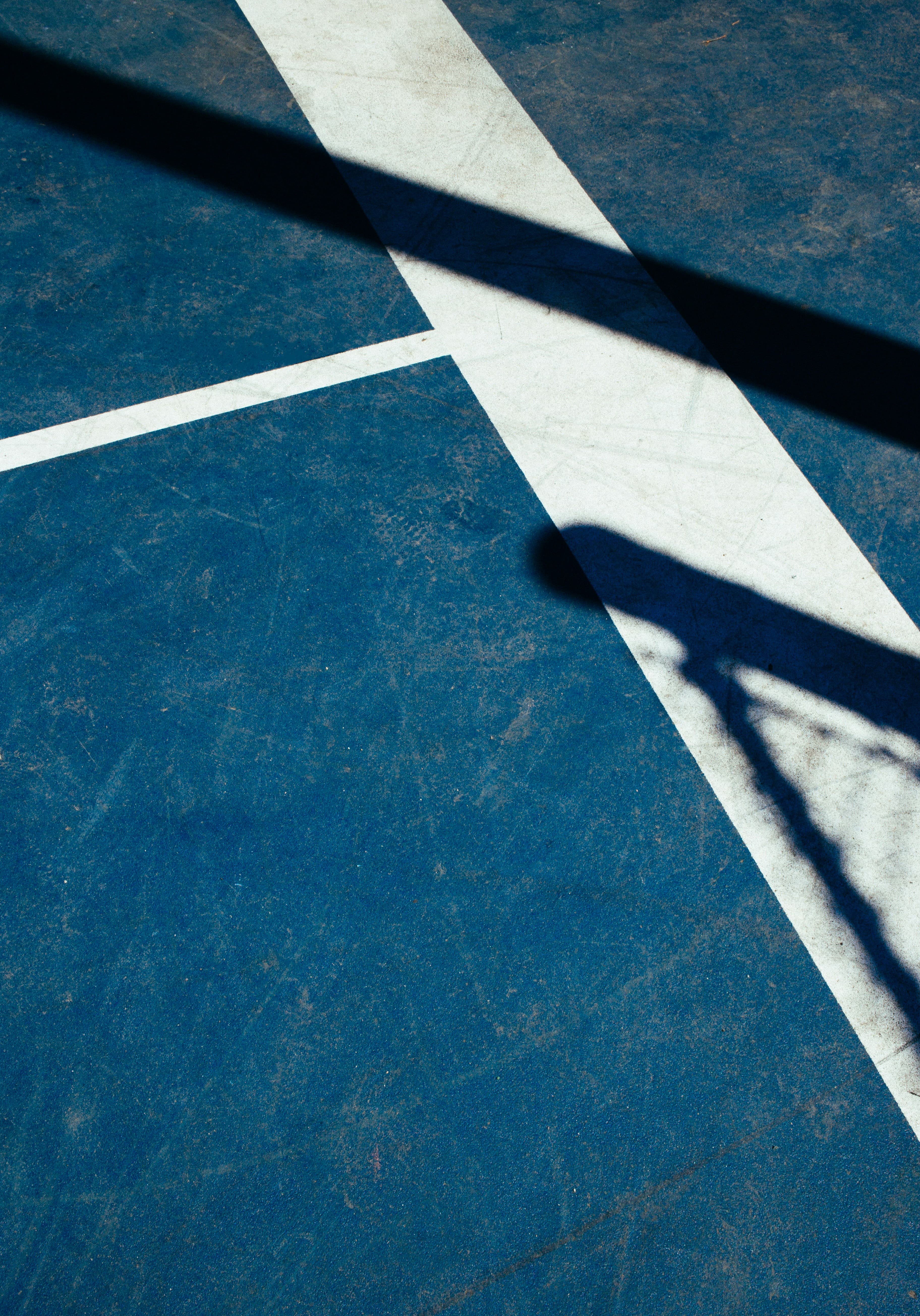 Padel court detail shot with white lines and diagonal shadow